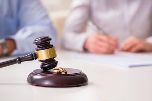 This is an image of a gavel and two gold wedding bands on the desk of a Meridian divorce attorney
